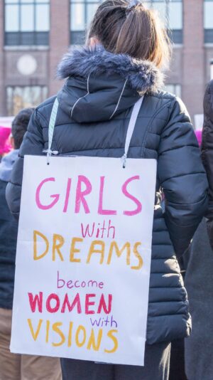 protest sign, girls become women with vision